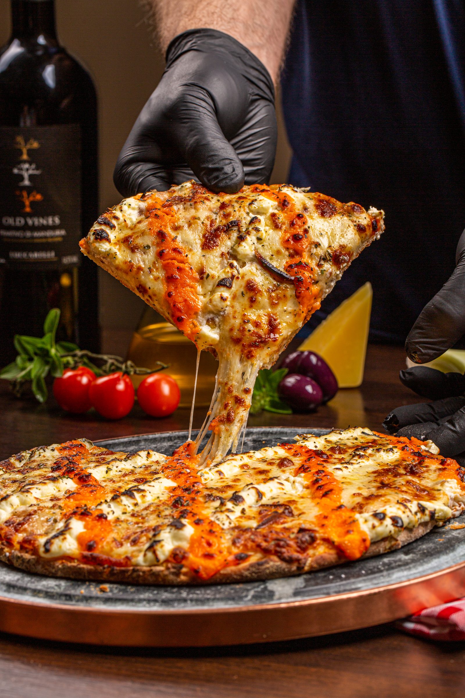 Fatia de pizza Cinco Queijos sendo levantada, com queijo derretido esticando